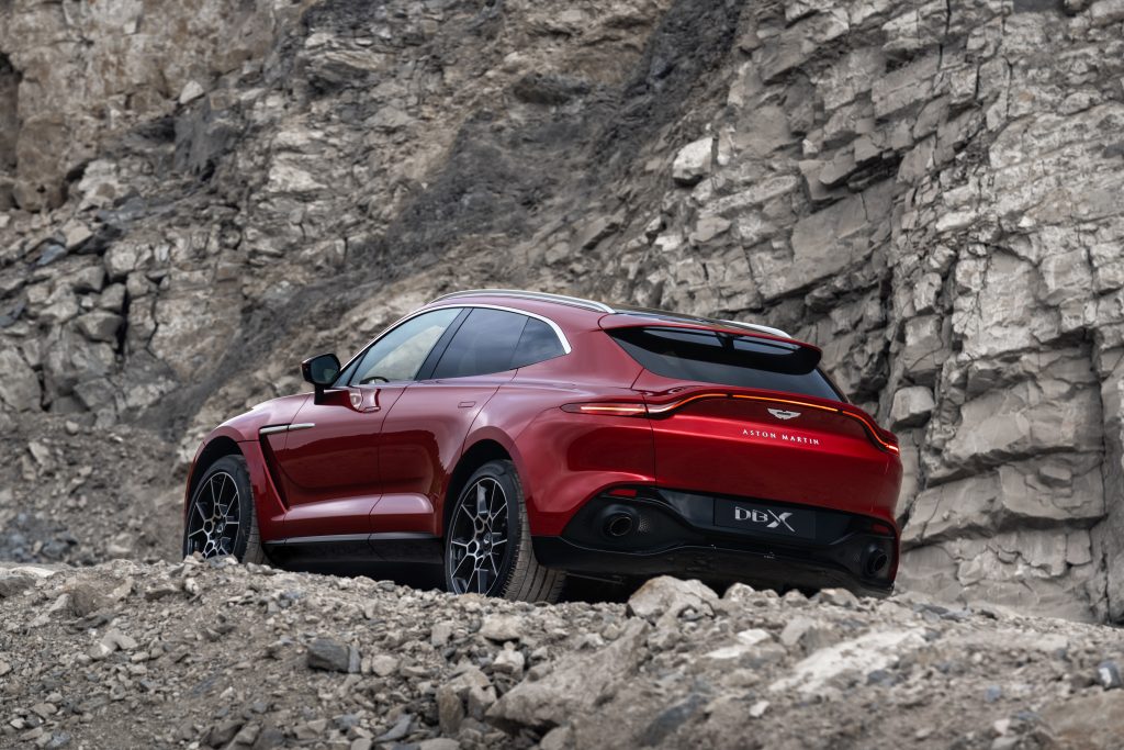 Aston Martin DBX going up rocking terrain, rear view